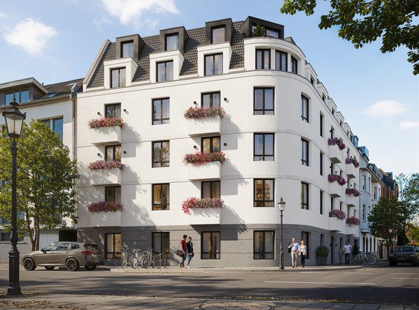 Außenansicht der eleganten, weißen Eckfassade der modernen Neubauwohnungen Düsseldorf-Rath eines Mehrfamilienhauses an einer Straßenecke. Das Gebäude verfügt über ein ausgebautes Mansarddach mit dunklen Gauben, ein graues Sockelgeschoss und französische Balkone mit rosa Blumenarrangements. Am linken Bildrand parkt ein grauer SUV, auf dem Gehweg sind Passanten zu sehen.