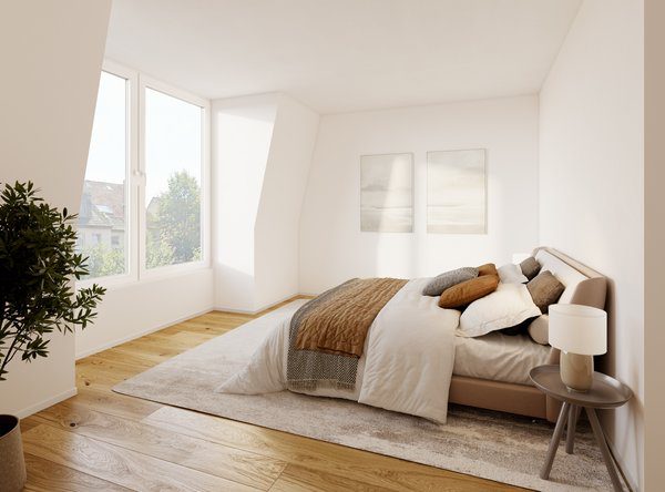 Hell eingerichtetes Schlafzimmer im Dachgeschoss mit Parkettboden und einer leichten Wandschräge. Ein großes Doppelbett ist mit weißen Laken, einer braunen Tagesdecke und gemütlichen Kissen ausgestattet. Neben dem Bett steht ein kleiner, runder Nachttisch mit einer Tischlampe, und an der hinteren weißen Wand hängen zwei dezente, quadratische Bilder. Ein großes Fenster auf der linken Seite lässt Tageslicht herein und gibt den Blick auf Bäume frei.